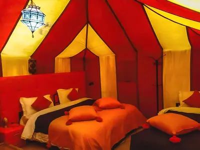a bedroom with two beds in a red room at Sahara Deluxe Camp in Merzouga