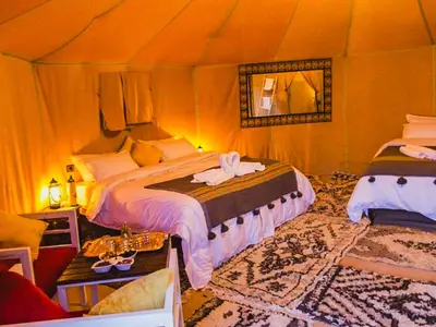 a bedroom with two beds in a tent at Sahara Deluxe Camp in Merzouga