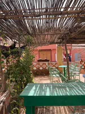 a green table and chairs under a wooden pergola at Auberge haut atlas in Tinerhir
