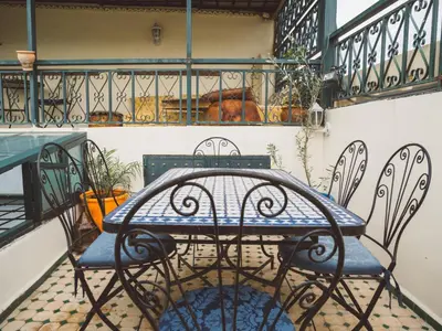 a table with two chairs and a blue table and chairsearcher at Dar Chrif Idrissi in Fès
