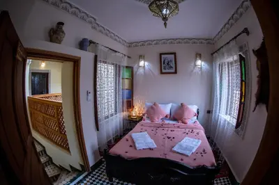 a bedroom with a bed with pink sheets and pillows at Dar alhaja rahma in Fès