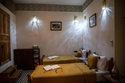 two beds in a room with lights on the wall at Dar alhaja rahma in Fès