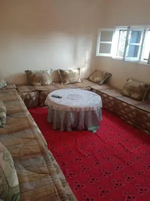 a room with a couch with a table on a red carpet at appartement au centre ville in Beni Mellal