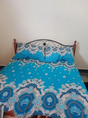 a bed with a blue comforter and pillows at appartement au centre ville in Beni Mellal