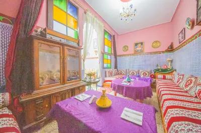 a room with two tables and a room with pink walls at Maison Adam in Fès