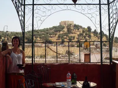 a woman standing in a restaurant with a view of a castle at Maison Adam in Fès