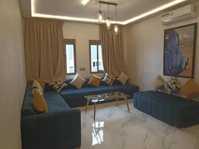 a living room with two blue couches and a table at Appartement luxueux proche de tout in Fès