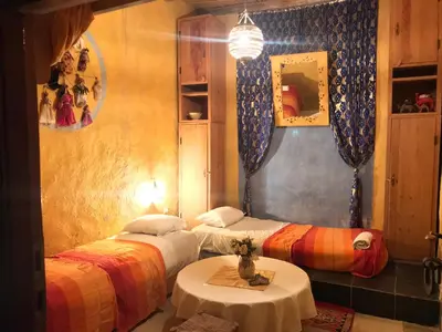 a room with two beds and a table in it at Auberge Chez Julia in Merzouga