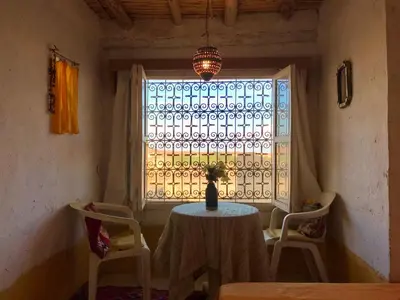 a table and chairs in a room with a window at Auberge Chez Julia in Merzouga