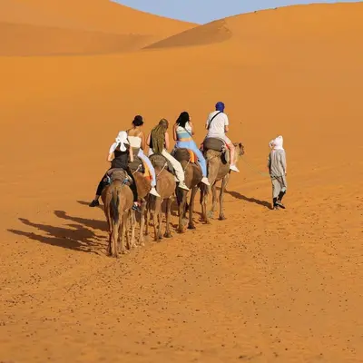 a group of people riding horses in the desert at Sahara Magic luxury Camp in Merzouga