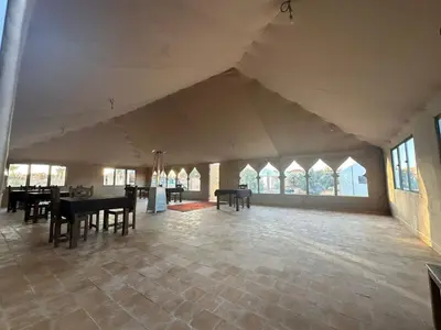a large room with tables and chairs and windows at Sahara Magic luxury Camp in Merzouga
