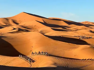 a group of people riding on horses in the desert at Sahara Magic luxury Camp in Merzouga