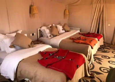 a group of four beds in a room at Sahara Magic luxury Camp in Merzouga