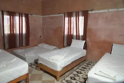 a room with two beds and two windows at CHEZ MANAR in Ouarzazate