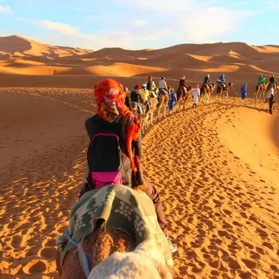a group of people riding horses in the desert at Desert night Camp in Merzouga