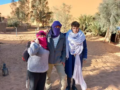 a group of three people standing in the desert at Oasis Desert Camp Obira in Merzouga