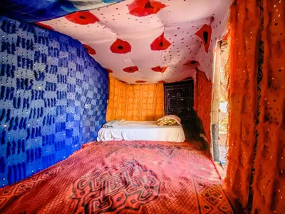 a bedroom with a bed with a red and blue wall at Oasis Desert Camp Obira in Merzouga