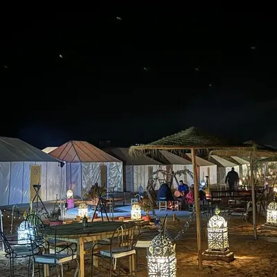 a group of tables with chairs and umbrellas at night at marvelous luxury desert stars in Merzouga