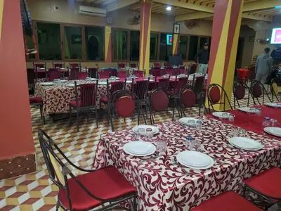 a room with tables and chairs with red and white tablecloths at El Menzeh Foundation in Rissani