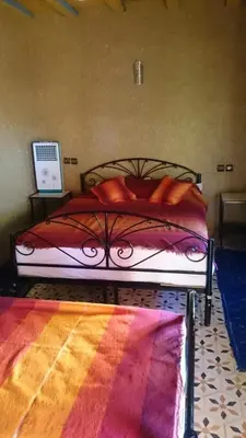 a bed with red pillows on it in a bedroom at El Menzeh Foundation in Rissani