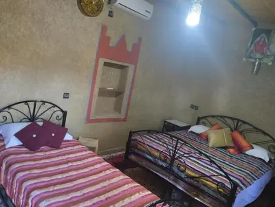 a bedroom with two beds and a mirror on the wall at El Menzeh Foundation in Rissani