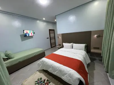a bedroom with a large bed and a green couch at COMPLEXE L'OASIS in Erfoud