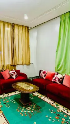 a living room with a red couch and a table at COMPLEXE L'OASIS in Erfoud