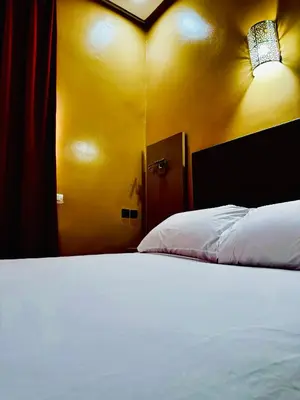 a bedroom with a white bed and a yellow wall at COMPLEXE L'OASIS in Erfoud
