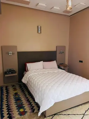 a bedroom with a large bed with a white comforter at COMPLEXE L'OASIS in Erfoud