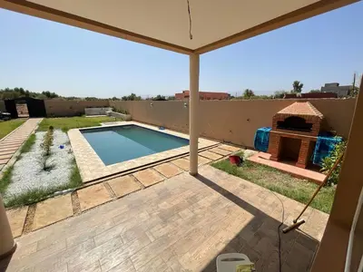 a backyard with a swimming pool and an umbrella at Villa 30 km a Marrakech in Marrakech