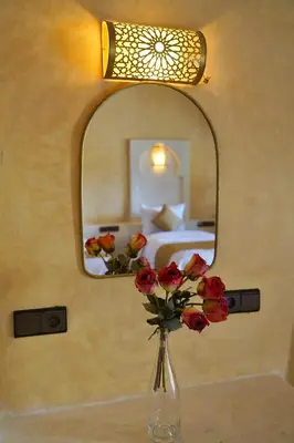 a vase of flowers on a table under a mirror at Hotel Sunset Palace in Merzouga