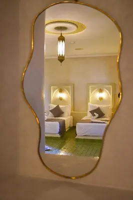 a bedroom with two beds and a mirror at Hotel Sunset Palace in Merzouga