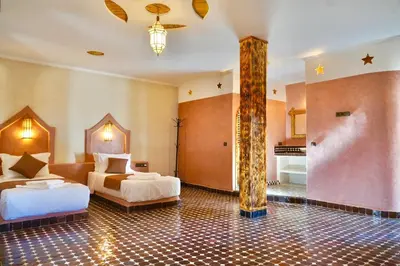 a hotel room with two beds and a bathroom at Hotel Sunset Palace in Merzouga