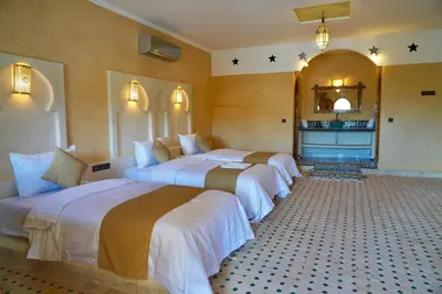 a hotel room with three beds and a fireplace at Hotel Sunset Palace in Merzouga