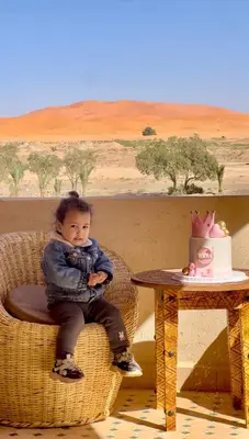 a young child sitting in a wicker chair next to a table at Hotel Sunset Palace in Merzouga