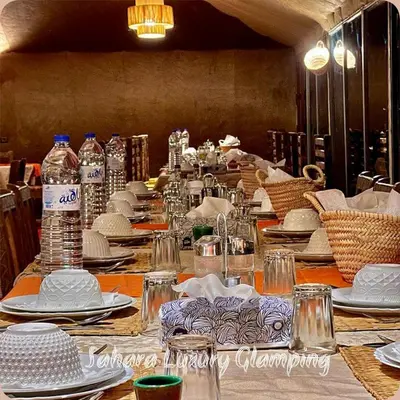 a long table with plates and bottles of water at Sahara Luxury Glamping in Merzouga