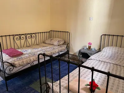 a bedroom with two beds and two tables with flowers at Dar Achraf in Fès