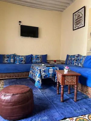 a living room with a blue couch and a table at Dar Achraf in Fès