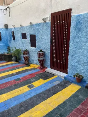 a red door on a blue building with colorful floors at Dar Achraf in Fès