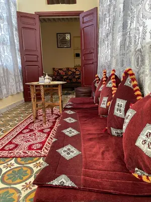 a room with red pillows on a couch with a table at Dar Achraf in Fès