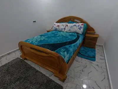 a bedroom with a wooden bed with a blue comforter at Tislite d azrou in Azrou