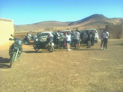 a group of people standing next to cars and a motorcycle at Auberge Camping Tafraoute Montagnes in Tafraoute Sidi Ali