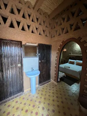 a bathroom with a sink and a bed in a room at Auberge Camping Tafraoute Montagnes in Tafraoute Sidi Ali
