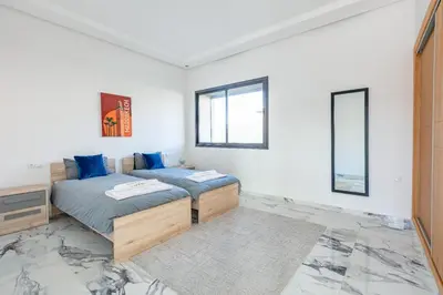 two beds in a room with white walls and windows at Villa Lella, piscine Chauffée, cuisinière in Marrakech