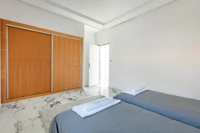 a bedroom with two beds and a wooden cabinet at Villa Lella, piscine Chauffée, cuisinière in Marrakech