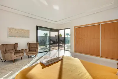 a bedroom with a large bed and two chairs at Villa Lella, piscine Chauffée, cuisinière in Marrakech
