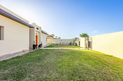 a backyard of a house with a grass yard at Villa Lella, piscine Chauffée, cuisinière in Marrakech
