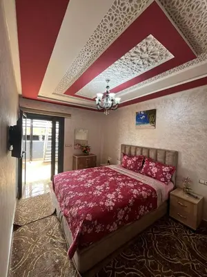 a bedroom with a large bed with red sheets at APPART HOTEL OUED EDDAHAB in Khenifra