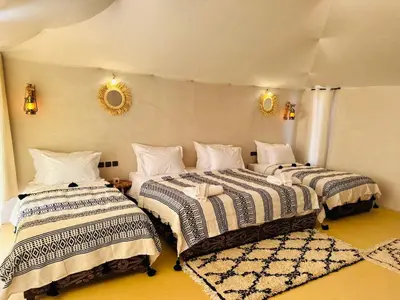 three beds in a room with mirrors on the wall at Luxury Sahara Camp in Merzouga
