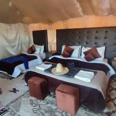 a bedroom with two beds and a hat on top at Luxury Sahara Camp in Merzouga